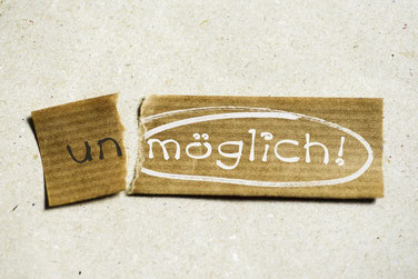Ein zerissenes braunes Papierstück mit dem Wort unmöglich 