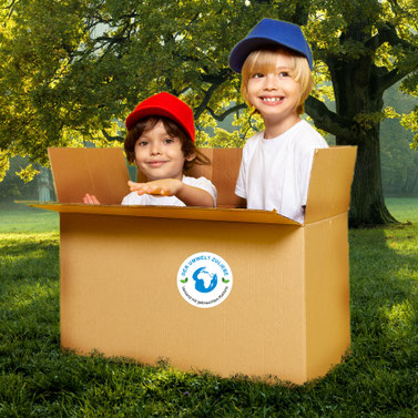 meinAufkleberladen - Verpackungsaufkleber blaue Erde - Der Umwelt zuliebe - Versand mit gebrauchten Kartons - klebt auf gebrauchten Karton in dem 2 Kinder spielen, Karton steht auf grüner Wiese mit großem Baum