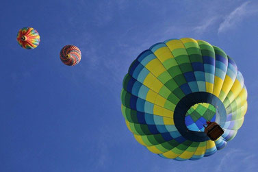 Ein Heißluftballon schließt zu zwei höheren Ballons am Himmel auf