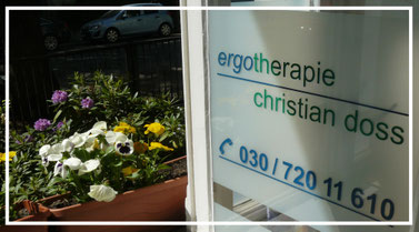 Offenes Fesnter mit Logo der Ergotherapie-Praxis Christian Doss. Davor Blumenkasten mit blühenden Stiefmütterchen