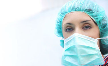 Mitarbeiterin mit Op-Haube und Mundschutz
