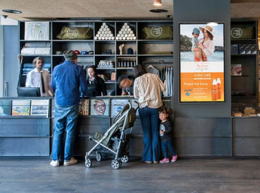 Familie mit Kind in einem Geschäft  neben Displayangebote