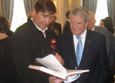 Bundespräsident Joachim Gauck (rechts) mit Manfred Wille beim Betrachten der Dokumentation zur Paddeltour im Rahmen der deutshen Einheit 1990 von Sulinger, Havelberger und Wolfsburger Schüklerinnen und Schülern
