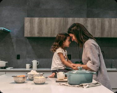 Frau hält ein sitzenden Mädchen auf dem Küchentisch an den Armen - Kindliche Kränkungen