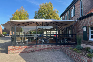 Ein in der Höhe verstellbarer Windschutz auf einer Terrasse in der Gastronomie vor einem Restaurant