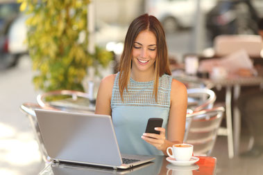Junge Frau mit Laptop und Smartphone