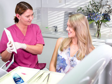 Zahnarztpraxis Dr. med. dent. Alina T. Ioana. Zahnmedizinische Fachangestellte erklärt Patientin die Möglichkeiten der ästhetischen Zahnmedizin.
