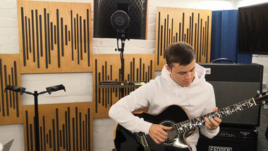 Gitarrenunterricht im Studio mit Gitarrenschüler mit Gitarrenlehrer Max Wegener mit E-Gitarre in der Hand. E-Gitarre und Marshall-Verstärker im Hintergrund.