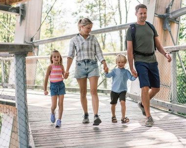 Familienurlaub am Traunsee – Familie bei Spaziergang auf Holzsteg mit Berg- und Seeblick im Salzkammergut