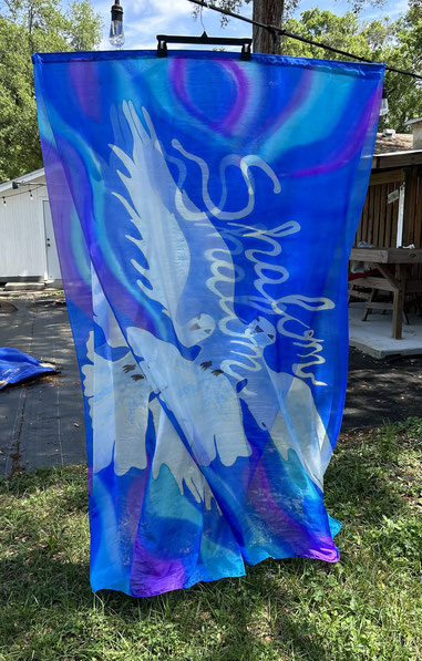 Long silk flags with a large white dove. Blue, turquoise and purple field.