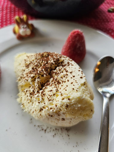 Cremiges Eierlikörmousse serviert auf einem Teller mit Himbeeren