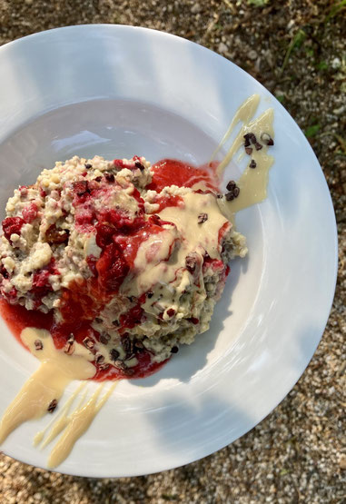 Weißer Teller mit vollwertig pflanzlichem Hirse-Porridge mit Erdbeerpüree, Mandelmus & Kakaonibs beim Meditations-Frühstück