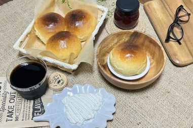 パンが盛り付けられたかご。アイスコーヒー。生クリームのお皿。眼鏡。