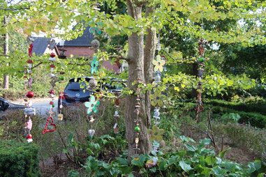  Deko Girlanden aus Holzelementen in verschiedenen Farben in einen Baum gehängt.