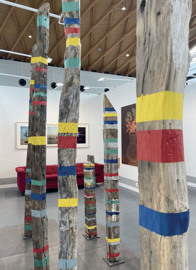 Kevin Clarke, Installation "Chromo-Family", Art Karlsruhe 2026 am Stand der Galerie Leander Rubrecht. Im Hintergrund die originale rote Couch der 80er Jahre des Kunstprojekts „The Red Couch – A Portrait of America“.