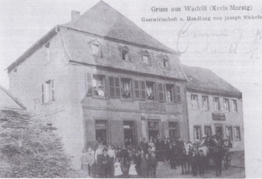 Dieses Bild, das 2001 zufällig auf einem Flohmarkt entdeckt wurde, zeigt das Gasthaus und Handelshaus Nickels gegenüber der Kirche in Wadrill nach der Aufstockung. Auf einem ältesten Foto aus dem Jahr 1910 ist das Dochgeschoss noch nicht ausgebaut.