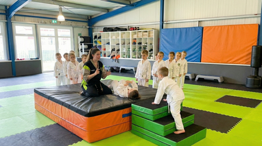 Trainerin zeigt Kindern eine Abroll- & Fall-Technik im Kurs Kinderkarate