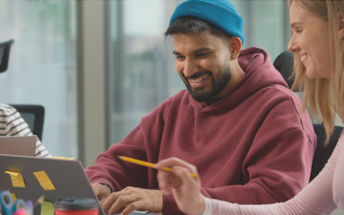 Team aus jungen Menschen arbeitet gemeinsam am Laptop und entwickelt kreative Konzepte – symbolisch für Zusammenarbeit in Organisationen und Non-Profit-Projekten.