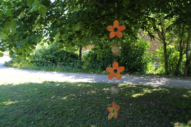 Girlande aus orange Holzblüten an einen Baum gehängt.