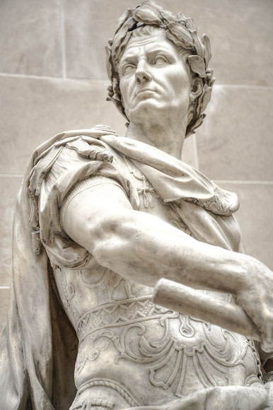 Close-up of a marble statue of a Roman leader in armor and laurel wreath, gazing sternly to the side.