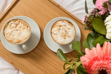 ピンクのバラの花束。コーヒーの入ったカップ&ソーサ。ページが開かれた書籍。