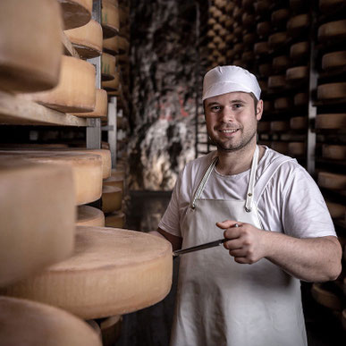 Person steht mit Hygienekleidung im Felsenkeller vor Käse