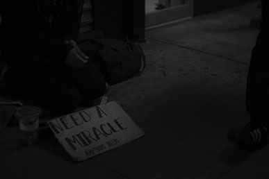 "I need a miracle"-Schild bei Obdachlosen