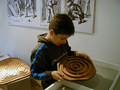 Ein Junge lässt die Murmel rollen in einem Holz-Labyrinth