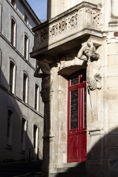 Porte en bois peinture rouge immeuble en pierre avec lumière soleil Niort Marais Poitevin Région Nouvelle-Aquitaine France Europe photo par Marie Deschene photographe Pakolla
