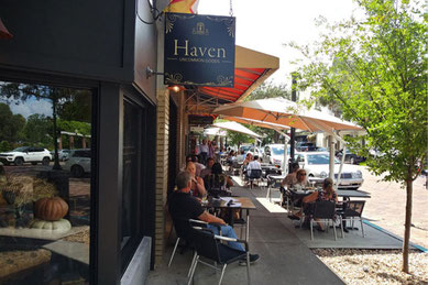 オーランド近郊ウィンター・パークのパーク・アベニュー。おしゃれなカフェやブティックが並び、テラス席で食事や会話を楽しむ人々が集う人気ショッピング＆散策スポット (Winter Park Park Avenue near Orlando with cafes, boutiques, and people enjoying outdoor dining).