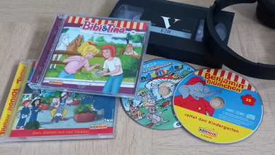 CDs von Bibi und Tina und Benjamin Blümchen liegen auf dem Boden, eine Videokassette und Kopfhörer daneben