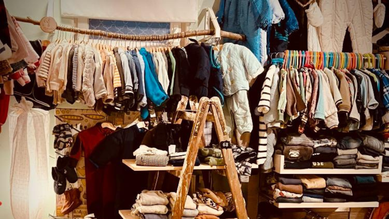 Regale mit Kinderbekleidung, die an Bügeln hängt und liegend gestapelt wurde