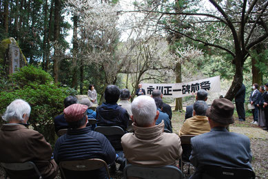 碑（左端）の前で吉田県委員長の挨拶を聞く参加者