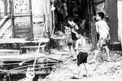 Picture in black and white: kids playing at throwing stones