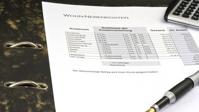 Fotoabbildung eines Formulars für Wohn-Nebenkosten mit einem Kugelschreiber,Taschenrechner und Aktenordner.Untertitel des Fotos:Formular Wohn-Nebenkosten