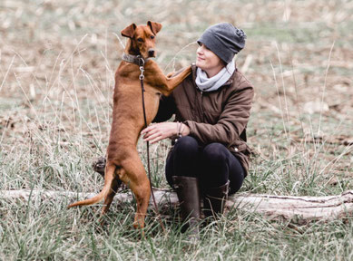 Ich sitze auf einem Baumstamm, mein Podenco steht neben mir, seine Vorderpfoten liegen auf meiner Schulter