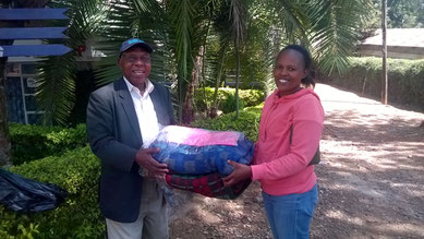 Mr. Mutugi hands Susan the two wool blankets...