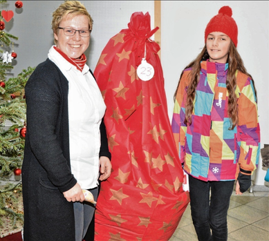 Filialleiterin Jana Panten (l.) freute sich mit der elfjährigen Adenisa aus Albanien über den hier noch verpackten Weihnachtsbaum.