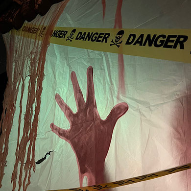 Ein roter Fingerabdruck auf weißer Leinwand sowie ein Band mit der Aufschrift "Danger"