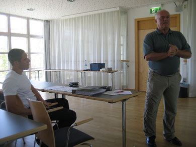 Karlheinz Langolf (stehend) begrüßt mit Reinhard Roth Teilnehmerinnen und Teilnehmer des Symposiums 