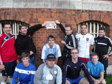 Die christlichen Fußballer bringen ein Schild an der Innenmauer der Justizvollzugsanstalt Braunschweig an. Dritter von links stehend JVA-Mitarbeiter Dietmar-Gero Meyer.