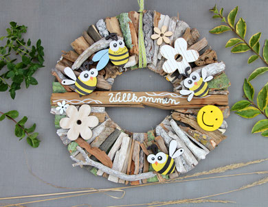 Braun-weiß Treibholz Kranz mit Willkommen-Beschriftung, Holzbienen, gelbem Smiley und weißen Holzblüten.