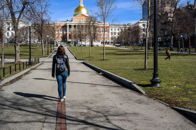 me a girl walking towards the massachusetts state hall on the freedom trail in boston in the park next to park street