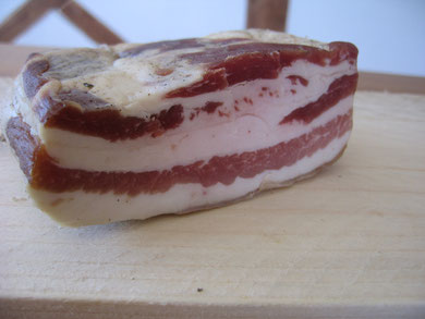 Ein Speckwürfel liegt auf einer Holzunterlage