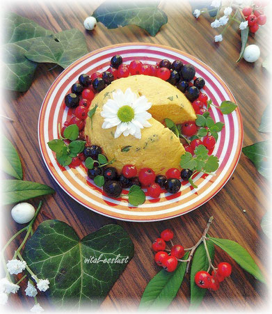 vegan cheese, veganer Käse mit Heidelbeeren und Johannisbeeren auf rotem Teller mit weißer Blüte