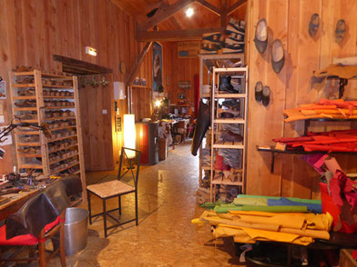 Cette image représente une vue de l'atelier des sabots d'isa, là ou l'on fabrique à la main et sur mesure des sabots qui se prennent pour des chaussures. Tout est en bois, paisible, il y a des semelles et des cuirs en couleur partout.
