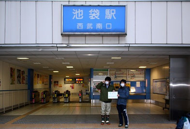 東京・池袋駅で集合。電車で秩父まで向かいます。「雪かきボランティア」という紙を掲げて、参加者を待つ山田君（右）たち。