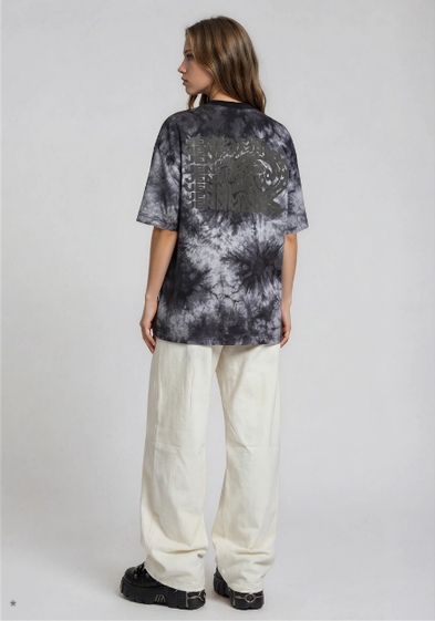 model wearing light baggy denim washed-out pants from the back with light grey batik shirt with black print on back side