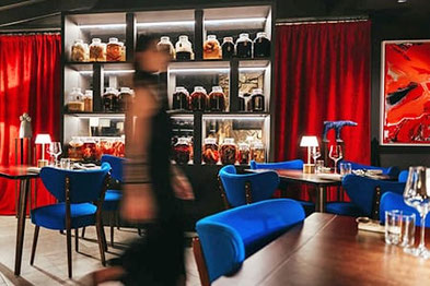 Eleganter Gastraum im OMNIA Plant-Based Restaurant auf der Seiser Alm mit offenem Fermentationsregal, stilvollem Ambiente und exklusivem veganem Fine Dining.