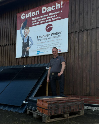 Dachdeckermeister Leander Weber in Penig vor Firmenbanner mit Solarmodulen und Dachziegeln